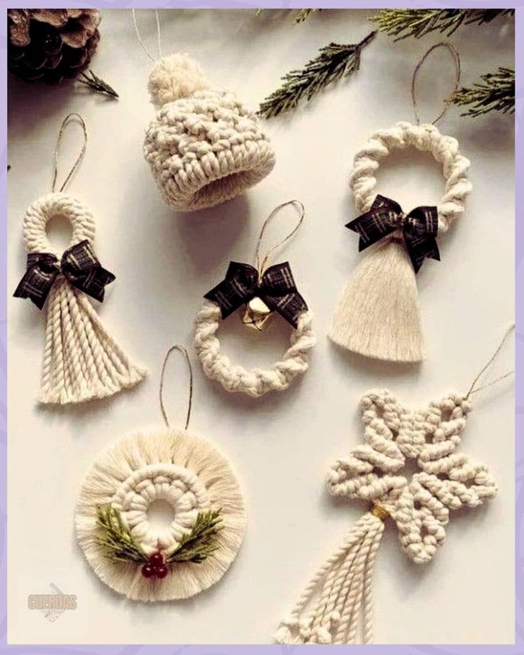 crocheted ornaments with bows and bells are arranged on a white tablecloth, surrounded by pine cones