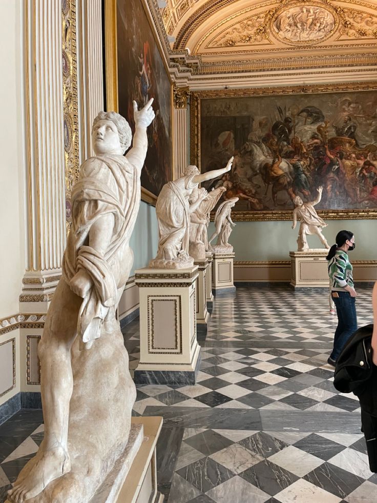 people are looking at statues in an art museum with paintings on the walls and ceiling