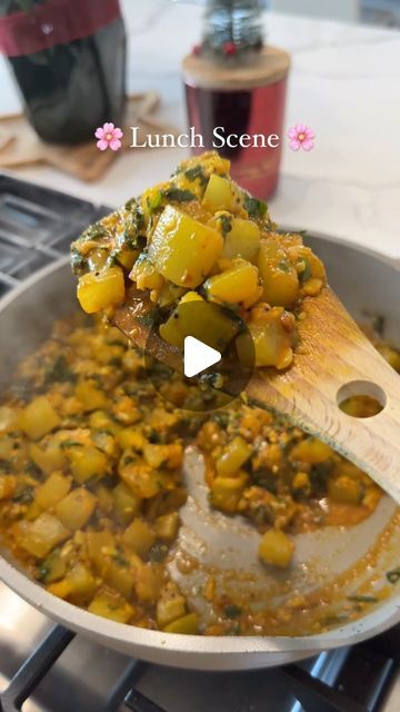 a pan filled with food sitting on top of a stove next to a wooden spoon