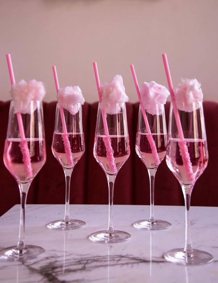 five wine glasses with pink straws in them