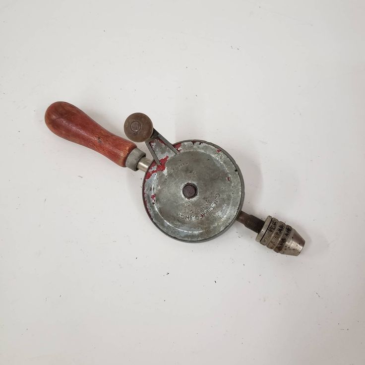 an old frying pan with a wooden handle on a white surface, next to a brush