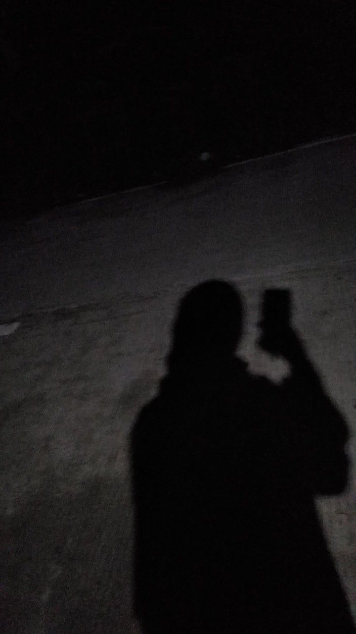 a person standing in the dark holding a cell phone