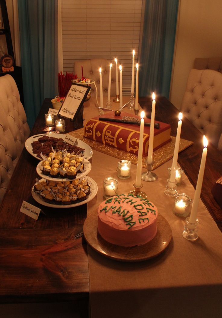 a table topped with cakes and candles next to a cake on top of a wooden table