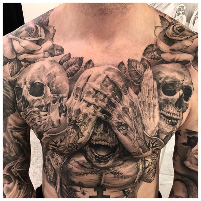 a man's chest with skulls and roses on it