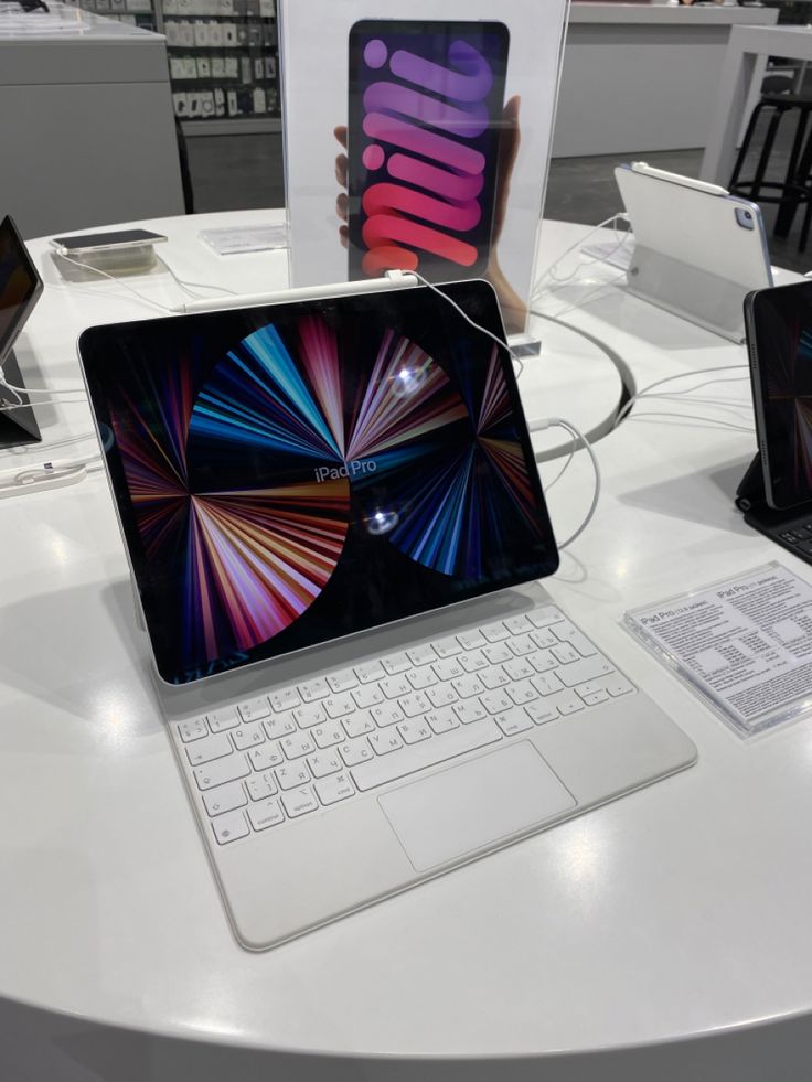 two laptops are sitting on a table with other devices in the background and one is open