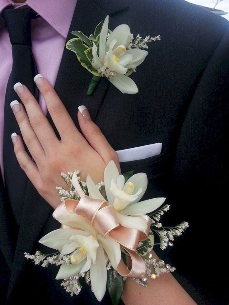 a man in a suit and tie with two boutonnieres on his lapel