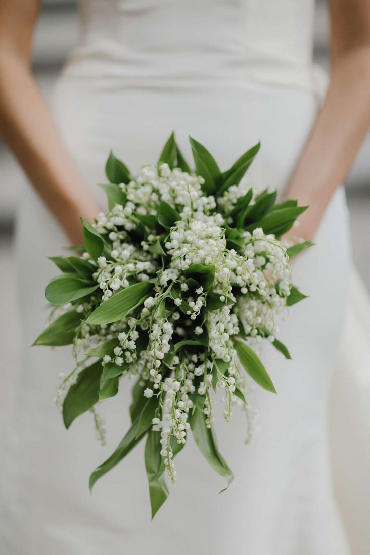 a bride holding a bouquet of white flowers