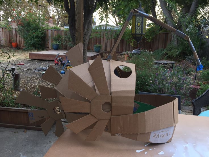 an open cardboard box sitting on top of a table in front of a tree and fence