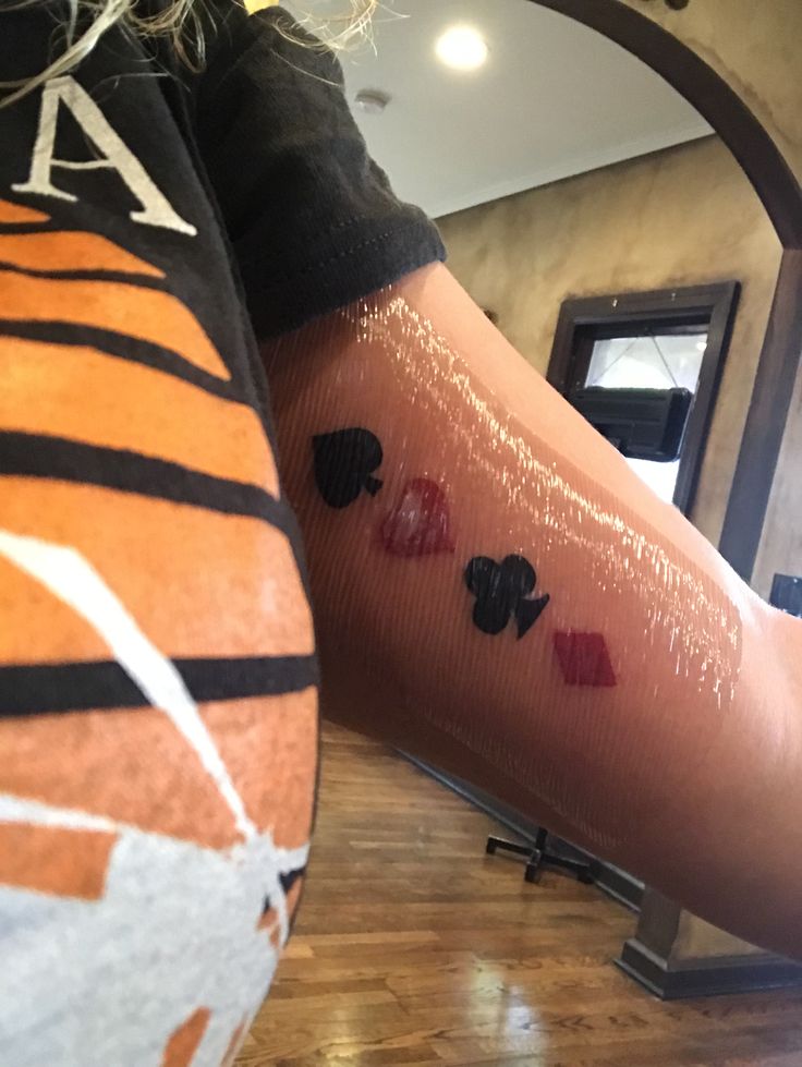 a person with tattoos on their arm and leg, both have hearts painted on them