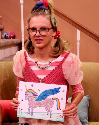 a woman sitting on top of a couch holding up a card with an unicorn drawn on it