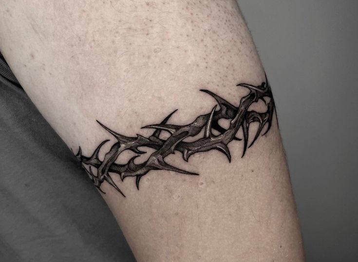 a black and white photo of a tattoo design on the left arm, with vines coming out of it