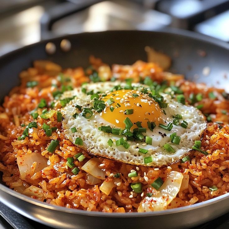 an egg on top of rice in a skillet with green onions and scallions