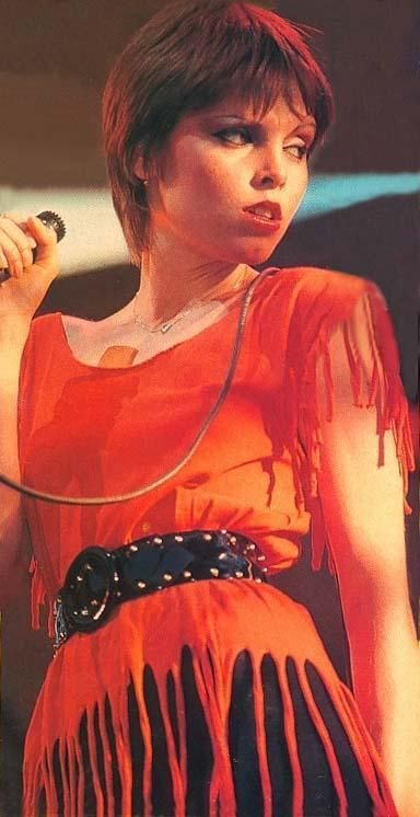 a woman in an orange dress holding a microphone