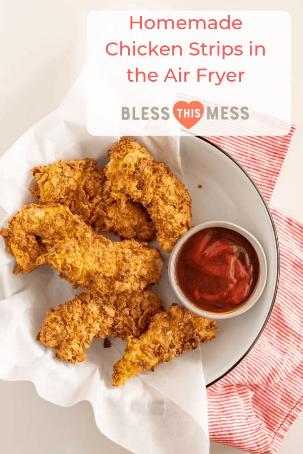 fried chicken strips in the air fryer on a white plate with ketchup