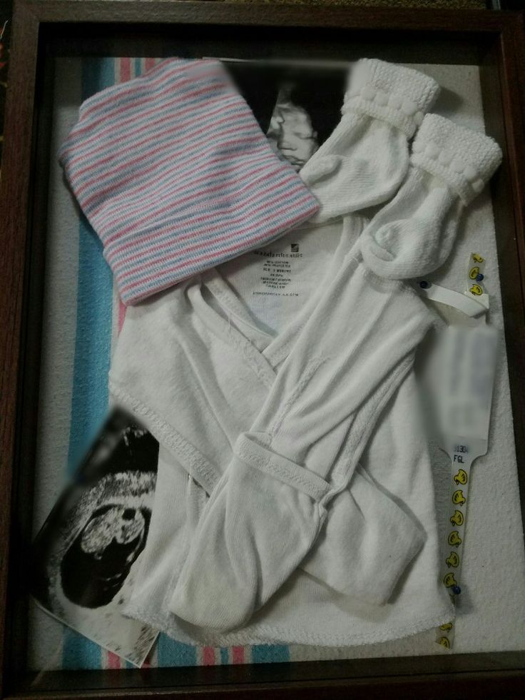 an image of baby clothes in a frame on the floor next to it's contents