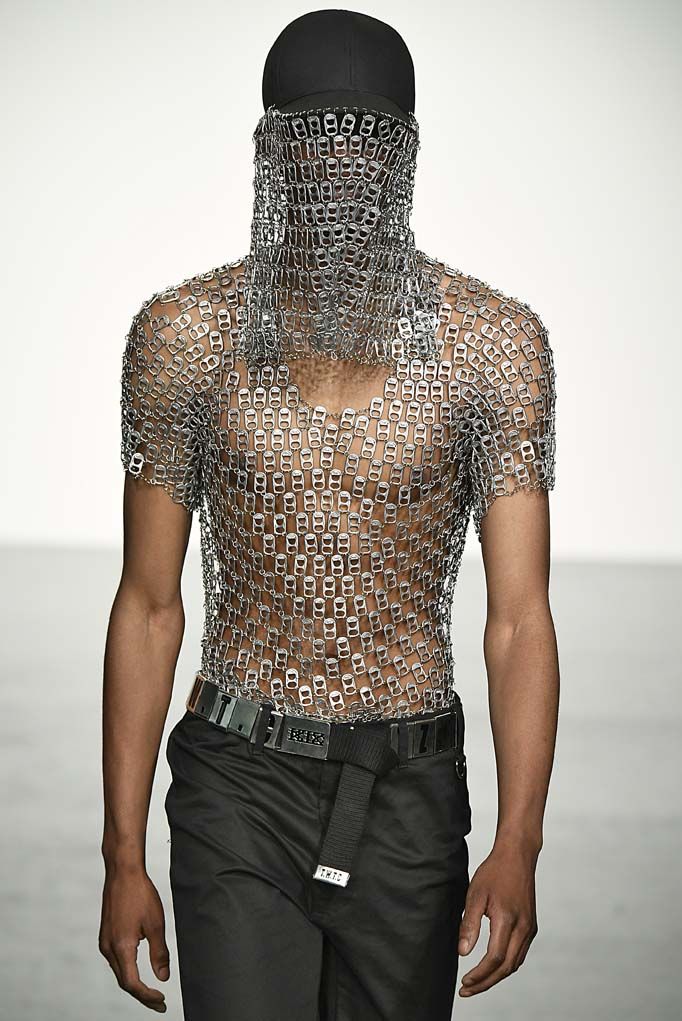 a man with chains on his face walking down the runway