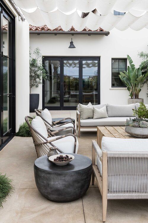 an outdoor living area with white furniture and potted plants