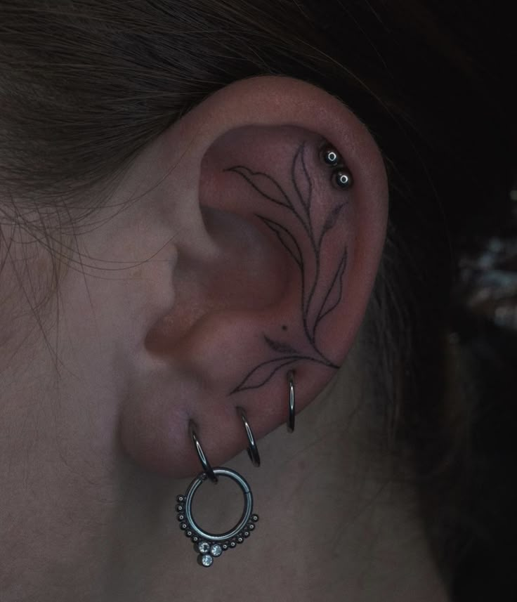 a woman's ear is adorned with piercings