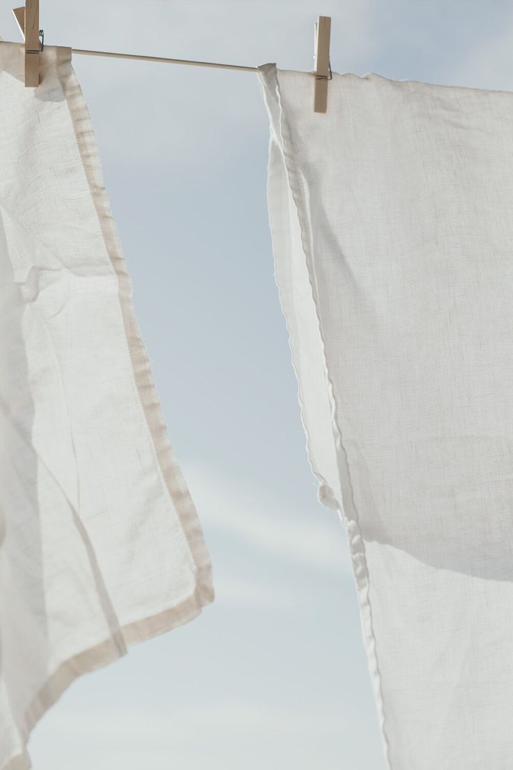 two white towels hanging on a clothes line with blue sky in the backround