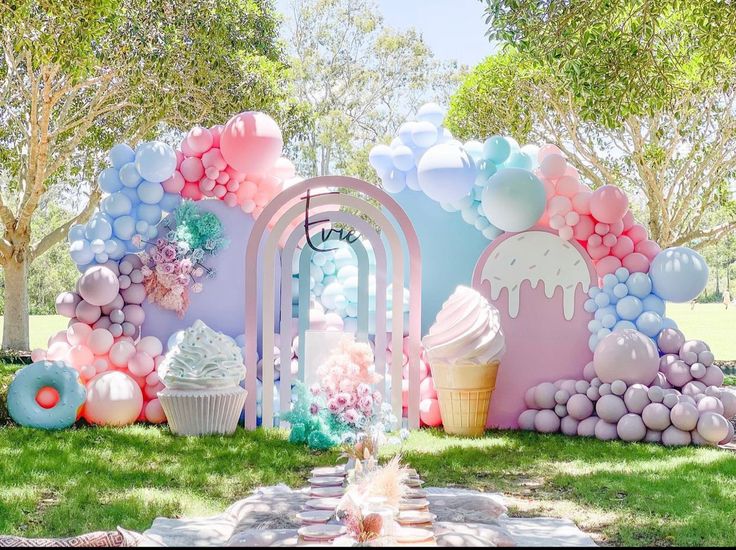 an ice cream themed birthday party with balloons, cake and cupcakes on the grass