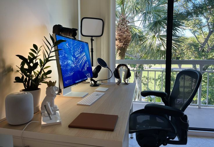 a desk with a monitor, keyboard and mouse on it in front of a window