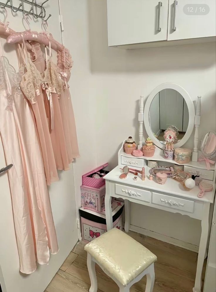 there is a dressing table with pink dresses on it and a stool in front of the mirror