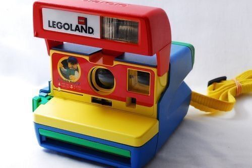 a toy camera sitting on top of a blue and yellow object with a cord attached to it