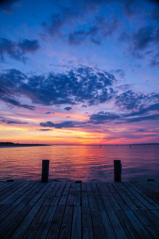 the sun is setting over the water and some docks