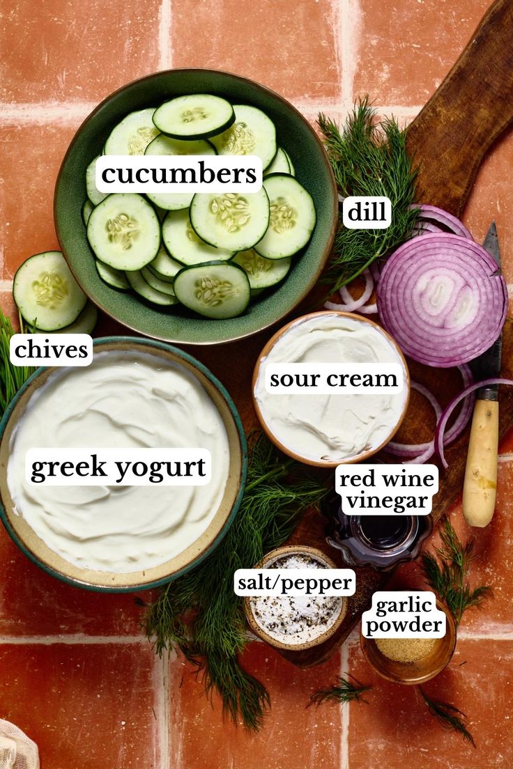 ingredients for cucumbers and cream in bowls on a tile background with words describing them