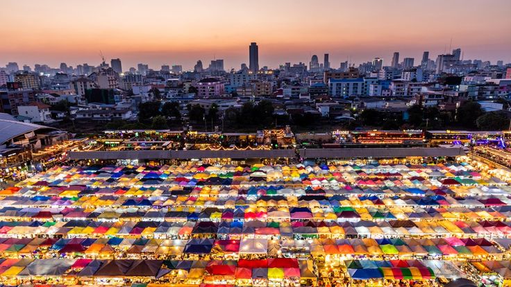 an aerial view of the city with many tents set up in front of it at dusk