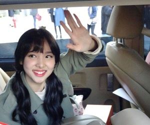 a woman sitting in the back seat of a car with her hand up and smiling