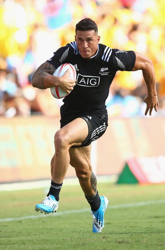 a rugby player running with the ball in his hand and people watching from the stands