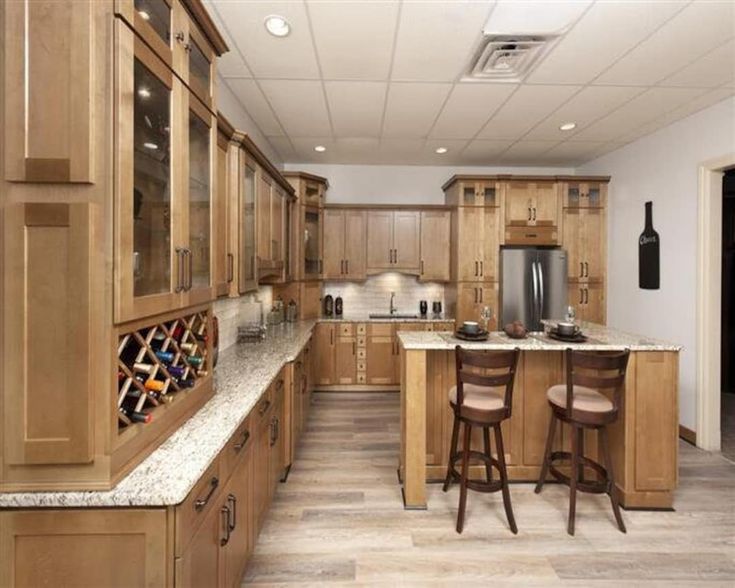 a large kitchen with wooden cabinets and marble counter tops, along with two bar stools