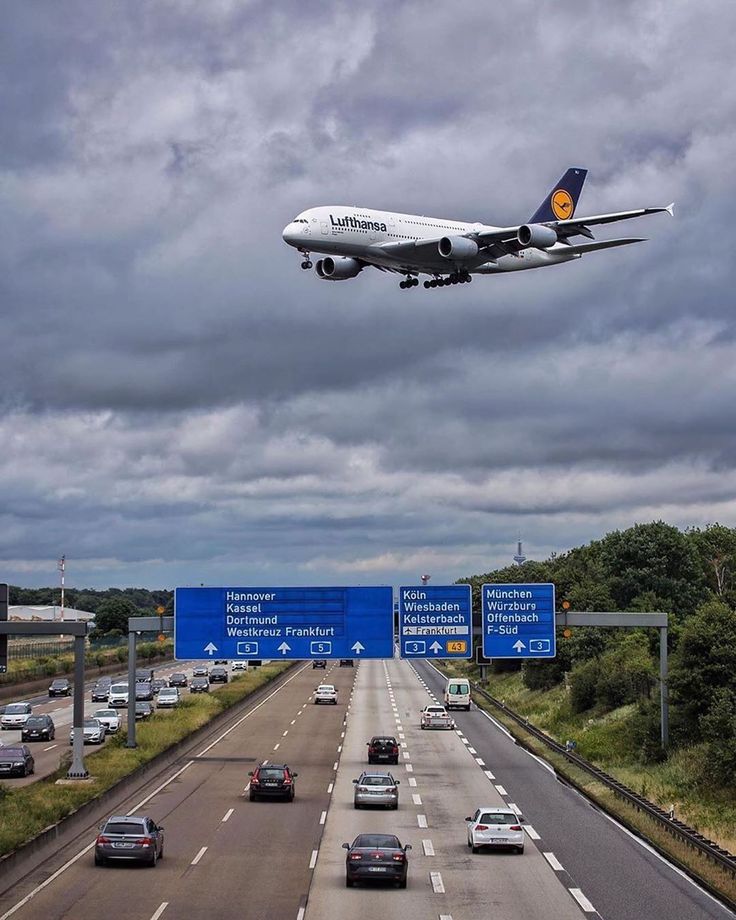 an airplane is flying over the highway with cars driving on it and another plane in the sky