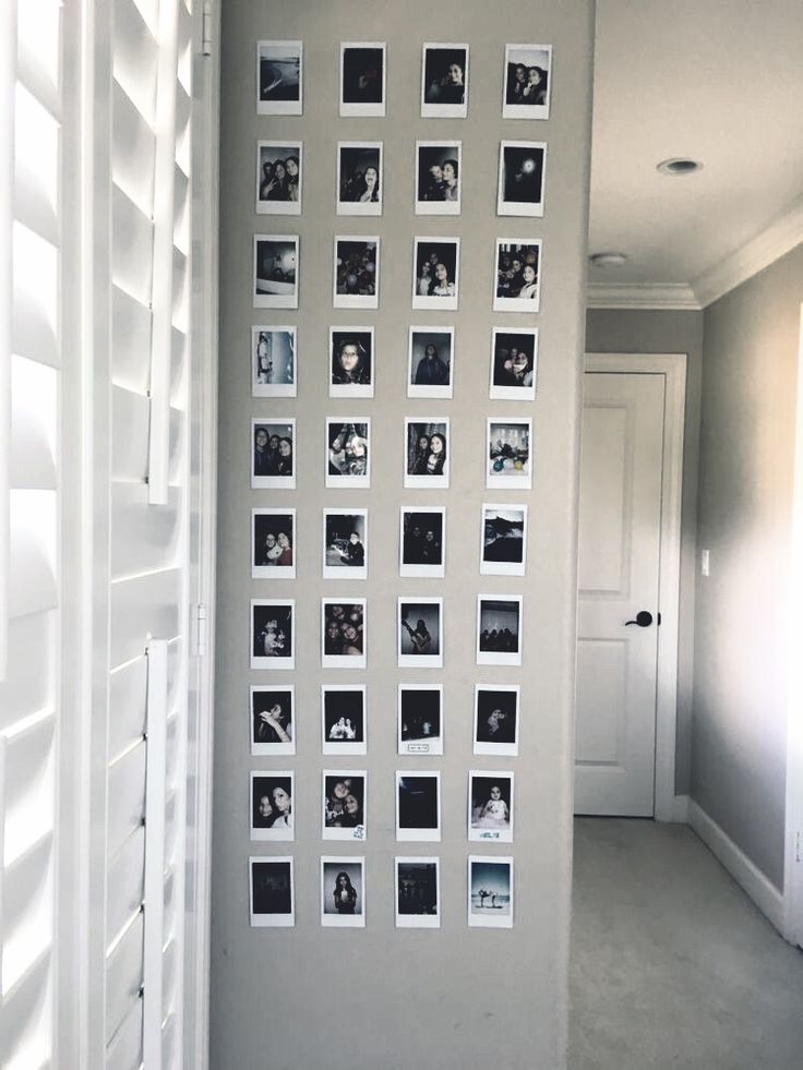 a white wall with pictures on it and shutters in the hallway between two rooms