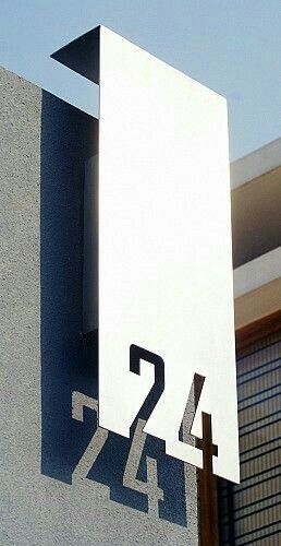 a house number sign on the side of a building with a sky in the background