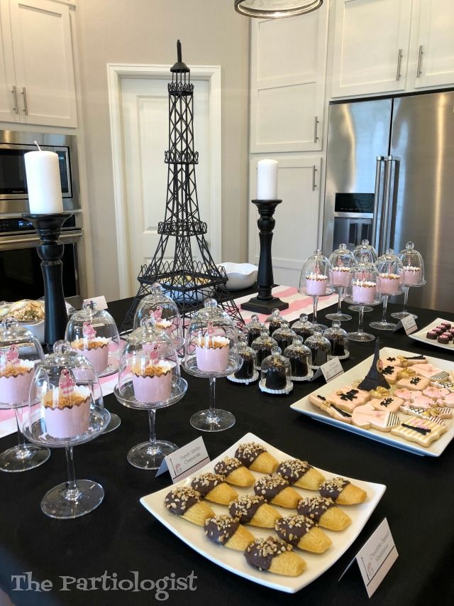 a table topped with lots of desserts next to a tall eiffel tower