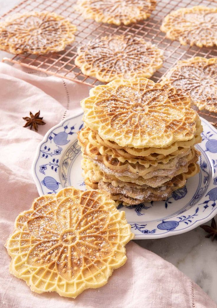 a stack of pancakes sitting on top of a blue and white plate covered in powdered sugar