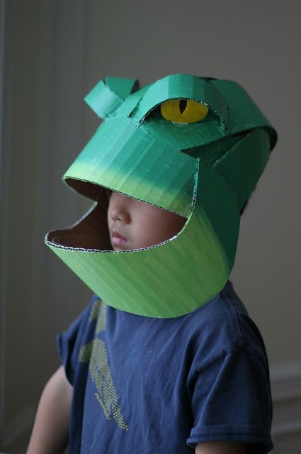 a young boy wearing a green paper hat with yellow eyes