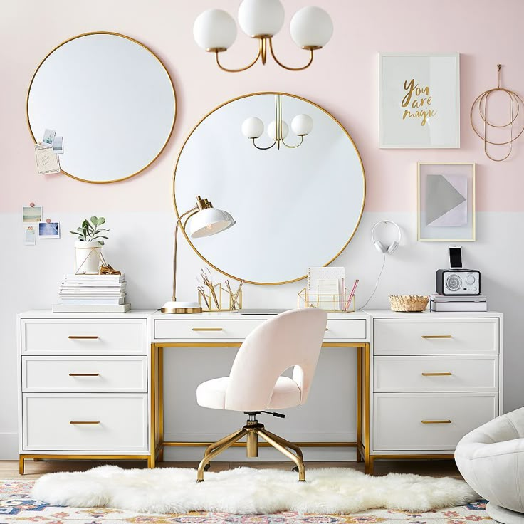 a white desk topped with a round mirror next to a chair and a table lamp