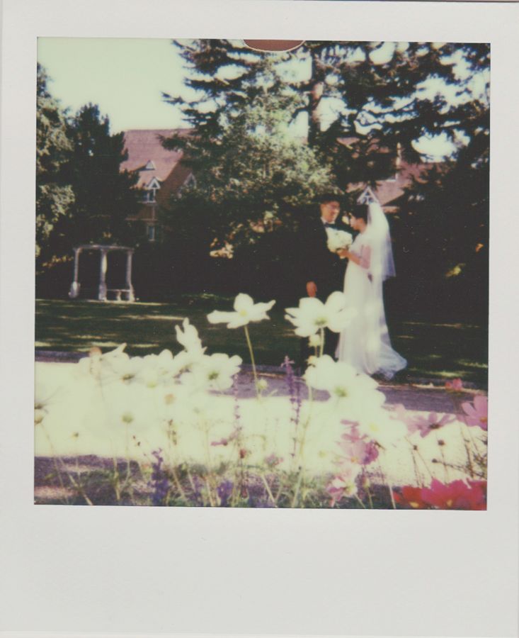 an old photo of a bride and groom standing in front of some flowers on the grass