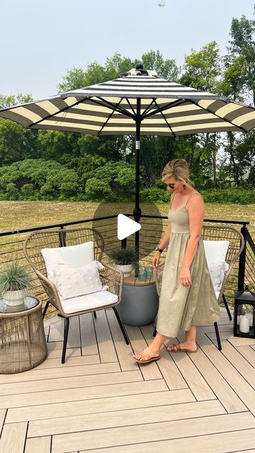 a woman standing under an umbrella on top of a wooden deck