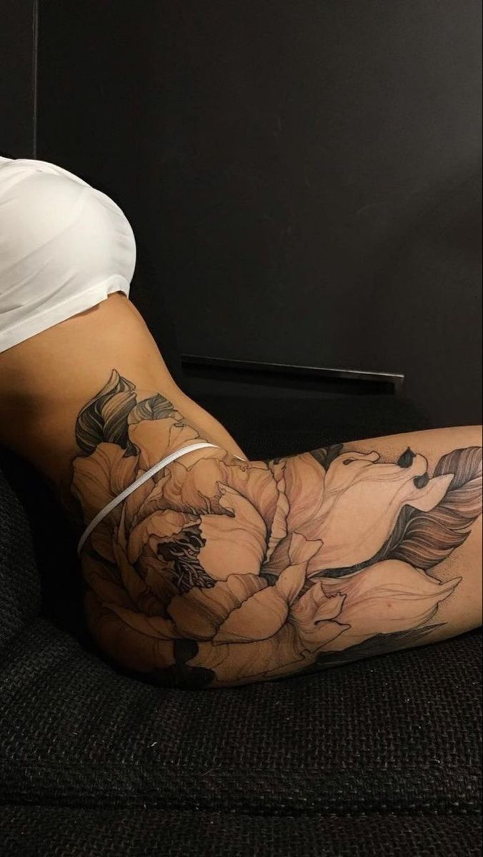 a woman sitting on top of a couch next to a black and white flower tattoo