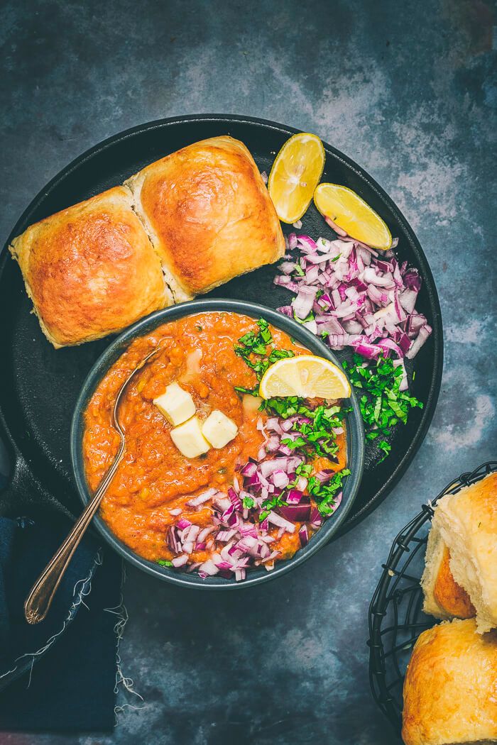 a bowl of soup with bread and vegetables on the side, along with other food items