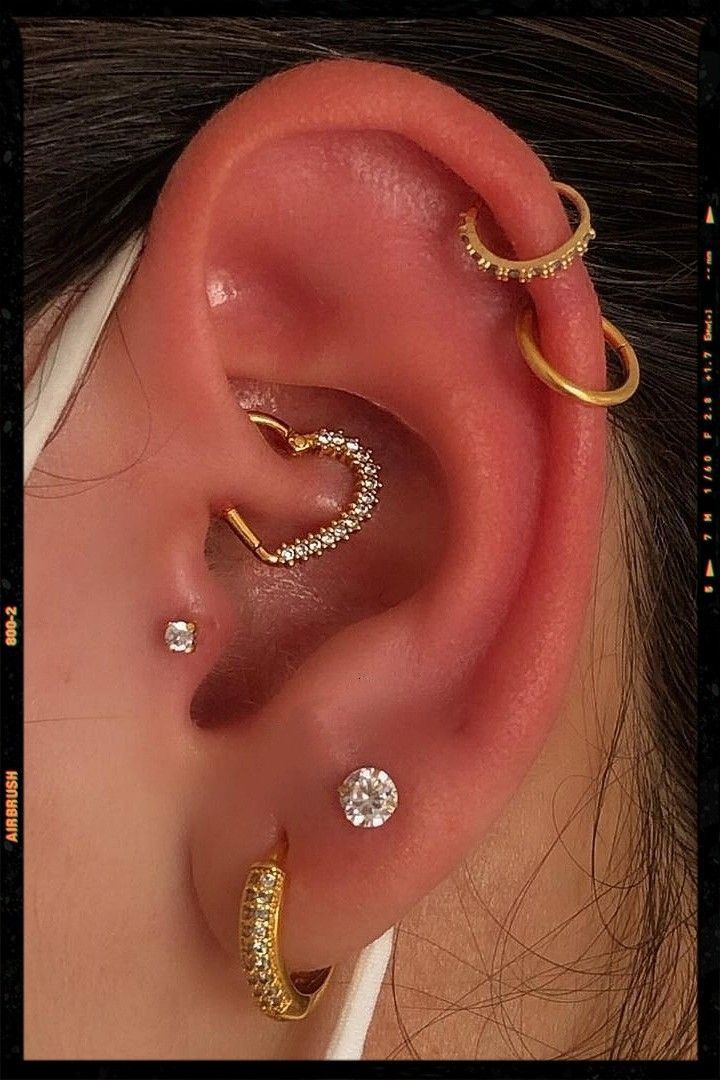 a woman wearing three different types of ear piercings on her left side of the ear