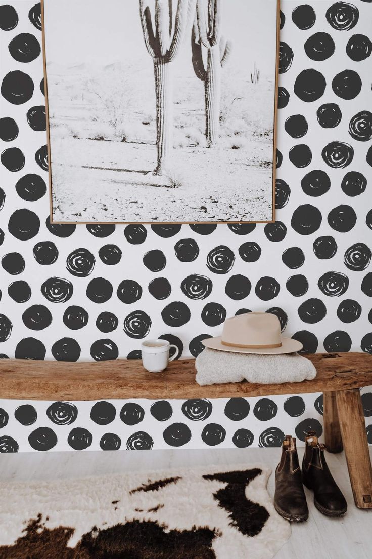 a black and white patterned wall with a wooden bench in front of it that has a hat on top of the bench