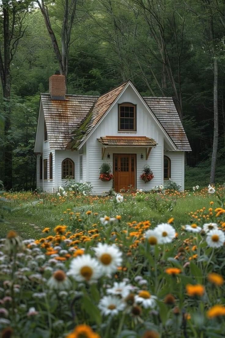 a white house surrounded by flowers and trees