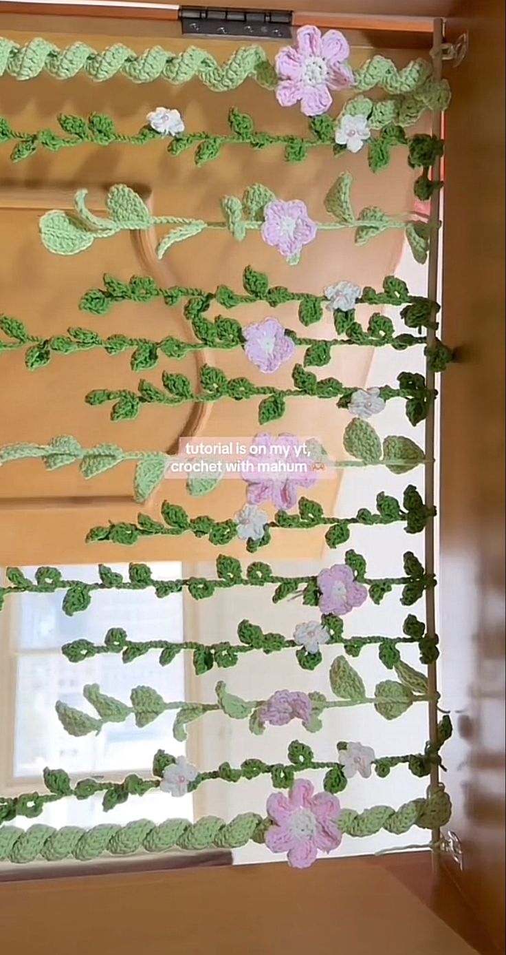 the window is decorated with green and purple paper flowers, which are attached to wooden slats