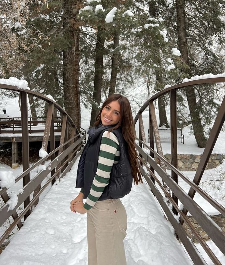 a woman standing on a bridge in the snow