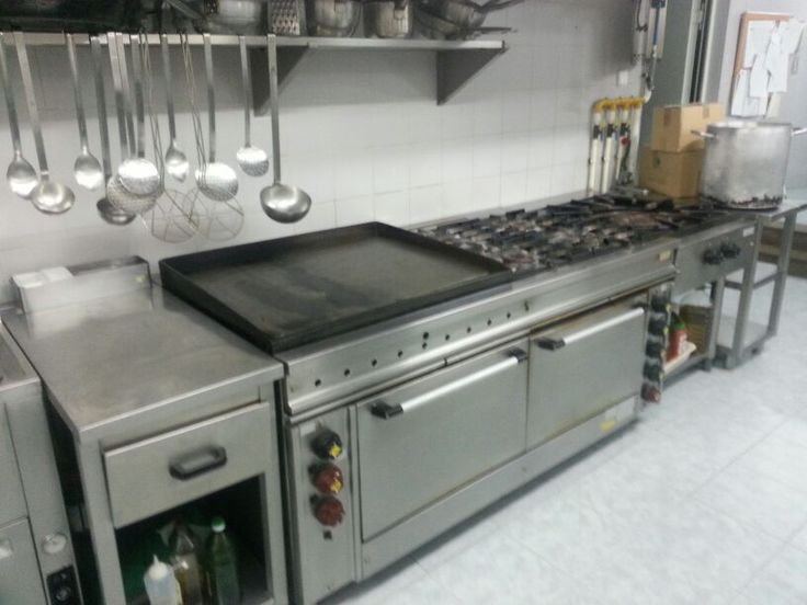 an industrial kitchen with stainless steel appliances and hanging utensils above the stove top